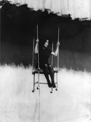 A black and white picture of Yoko Ono sitting on a swing.