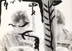 A self-portrait by Gabriele Stötzer, painted with black patterns, capturing herself in the mirror with an analog camera.