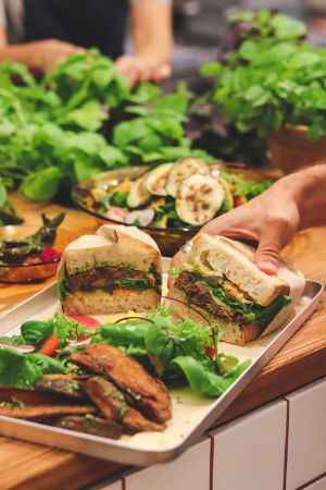 A tray with sandwiches, salad and roasted vegetables.