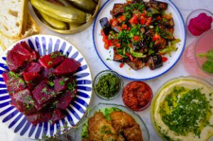 Various colourful vegetarian dishes, including hummus, an aubergine salad, a beetroot salad and roasted cauliflower.
