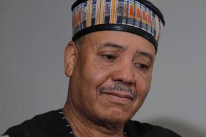 Majid Bekkas blickt auf eine Gimbri, die er in den Händen hält.
