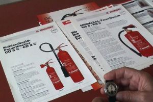 Anleitungen für verschiedene Feuerlöscher sowie eine Hand, die eine Uhr hält.