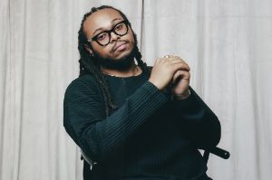 Portrait of Immanuel Wilkins sitting on a chair with his hands folded.