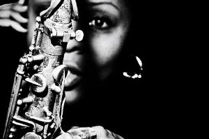 Schwarz-weißes Porträt von Matana Roberts, die unscharf hinter einem Saxofon zu sehen ist