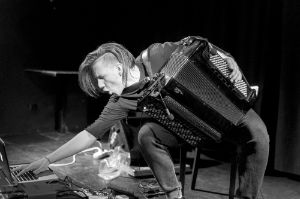 Zbigniew Chojnacki holds an accordion in his hands while adjusting something on his laptop.