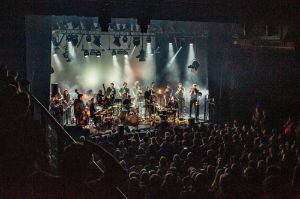 Gard Nilssen’s Supersonic Orchestra auf einer Bühne vor einem mit Publikum gefüllten Zuschauersaal.