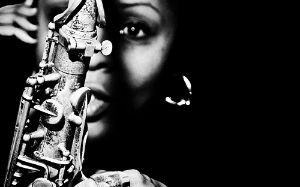 Schwarz-weißes Porträt von Matana Roberts, die unscharf hinter einem Saxofon zu sehen ist