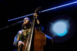 Die Komponistin, Sängerin und Kontrabassistin Fuensanta während eines Live-Auftritts. Ihre Augen sind geschlossen, vor ihrem Körper hält sie einen Kontrabass. Blaue Lichter sind im Hintergrund zu erkennen.