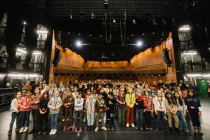 Viele Kinder und im Hintergrund einige Erwachsene stehen auf der Großen Bühne der Berliner Festspiele, hinter ihnen ist der Publikumsbereich hell erleuchtet.