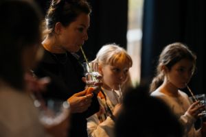 An adult and two children have glasses in their hands and striped straws in their mouths.