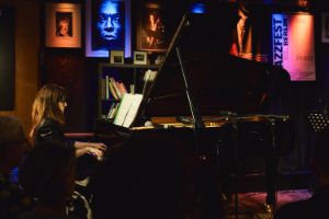 Marta Sánchez playing the grand piano in a leather jacket