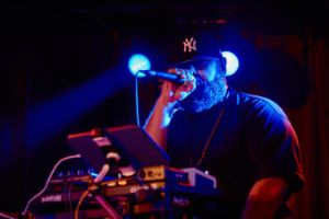 MC Dälek raps behind a mixing desk