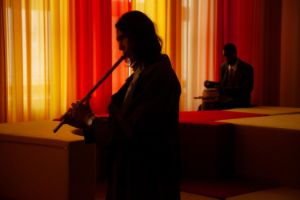 Silhouette einer Flöte spielenden Person in einem abgedunkelten Raum