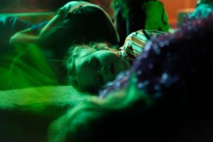 Ein Kind liegt mit geschlossenen Augen zwischen mehreren andern Kindern am Boden.