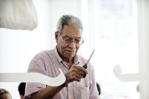 Fluxus artist Benjamin Patterson cuts strips of paper with scissors.