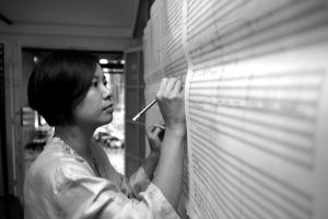 The composer uses a pencil to write in a large score on the wall.