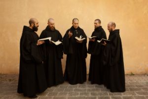 Fünf Mönche singen im Halbkreis mit Büchern in der Hand.