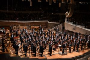 The entire orchestra stands on the stage, Kirill Petrenko on the podium facing the audience.