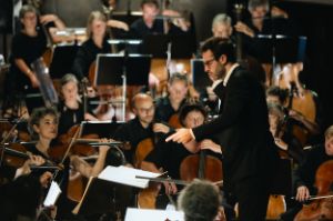 Dinis Sousa conducts, with the orchestra around him.