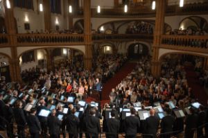 The choir faces Gijs Leenaars, who stands between the audience blocks in the Gethsemane Church.