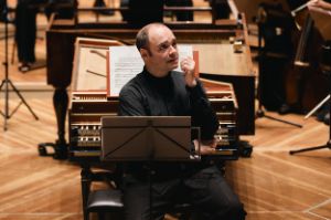 Alexander Melnikov sits with his back to the piano, a music stand in front of him.