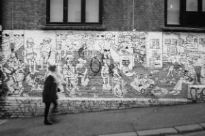 Woman in front of a brick wall with drawn graffiti