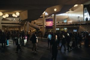 In einem Foyer bewegen sich viele Menschen, im Hintergrund ist das Plakat des Musikfest Berlin 2025 zu sehen.