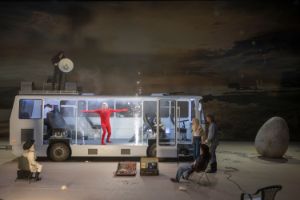Performer*innen stehen in und vor einem umgebauten Bus, aus dem kleine Feuerwerke schießen.