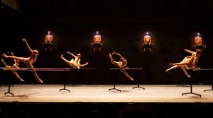 Four dancers with naked upper bodies touch each other in different places.