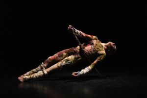 Performer*in in einem Kostüm aus verschiedenen bunten Stoffen
