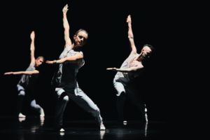 Three dancers in synchronised movement, arms at right angles