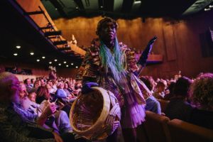 Performer stands with a basket in the audience rows