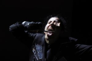 A person sticks out their tongue far and holds a knife blade to their mouth.