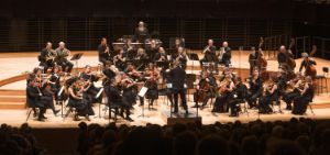 An orchestra sits on stage and plays.