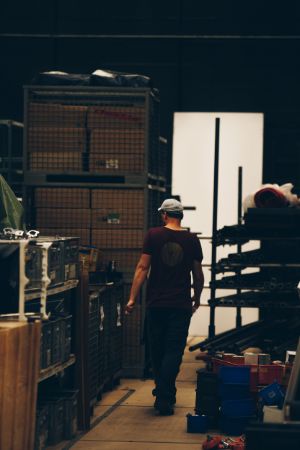 View into a storage room with various shelves and utensils, in which a man can be seen.