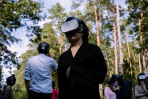 Personen mit VR-Brilen stehen in einem Wald und blicken in verschiedene Richtungen.