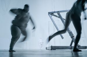 A scene from “Der Zauberberg”; several people are running across a large, white stage area. 