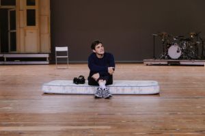 Der Schauspieler Benjamin Lillie sitzt in einer Szene aus der Inszenierung „Einfach das Ende der Welt“ auf einer am Boden liegenden Matratze.