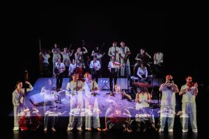 Musicians on stage are mirrored several times.