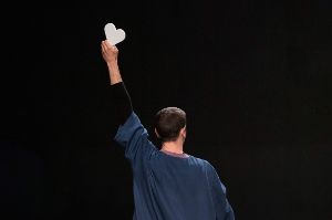 One man stands with his back to the camera and holds a white heart in the air.