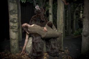 Ein Bär im Wald hält einen Mann in seinem Schoß.
