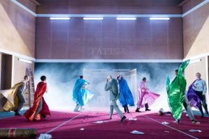 Colourfully dressed actors walk off the stage.