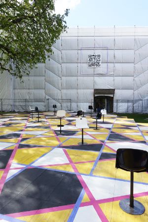 White and black swivel stools stand on a colourful surface in front of the Festspielhaus.