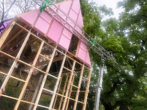 The scaffolding of a house with pink panels stands in the garden of the Haus der Berliner Festspiele.