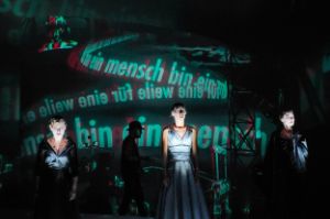 Vier Personen stehen vor einer Projektion, die spiralförmig Worte an eine Projektionsfläche wirft