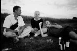 Zwei Männer und eine Frau sitzen entspannt auf einer Wiese. Das Bild ist in Schwarz-Weiß gehalten.