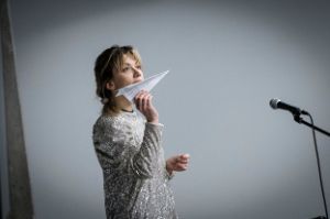 A woman holds a paper aeroplane in her hand.