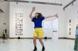 A woman jumps on the spot in an exhibition space.