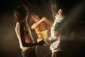 Three people are dancing together, one of them is wearing a jumper with sequins.