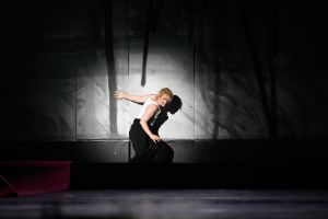 A person in the spotlight in front of a sprayed wall on stage